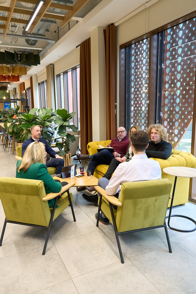 Group of professionals having a casual discussion in a modern office lounge.