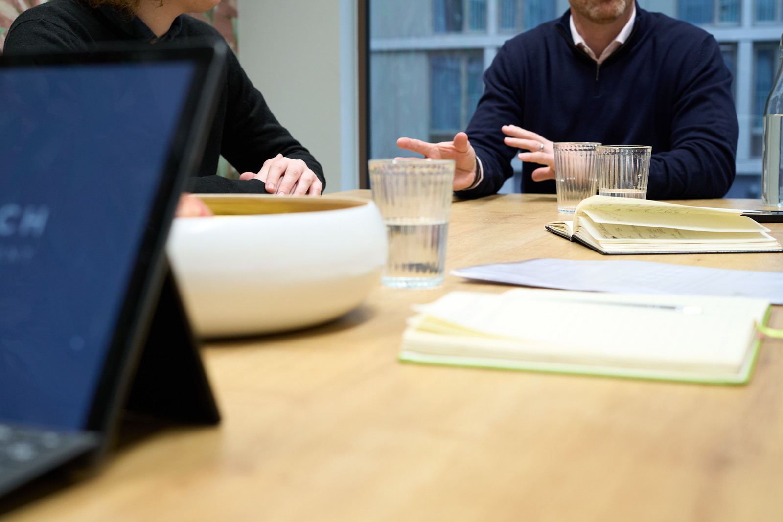 Business meeting with notebooks, glasses of water, and a laptop on the table